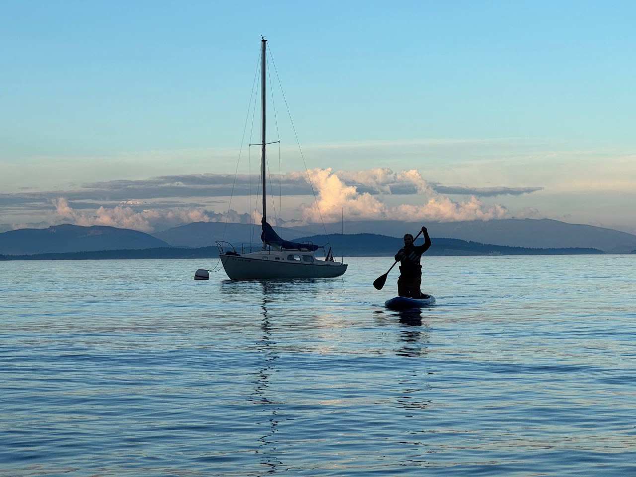 Sailboat and paddleboarder on calm water